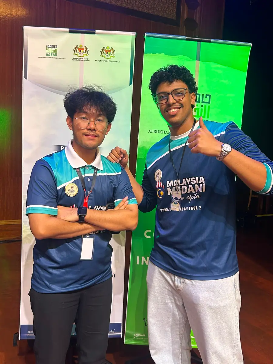 Standing with a teammate in front of event banners.