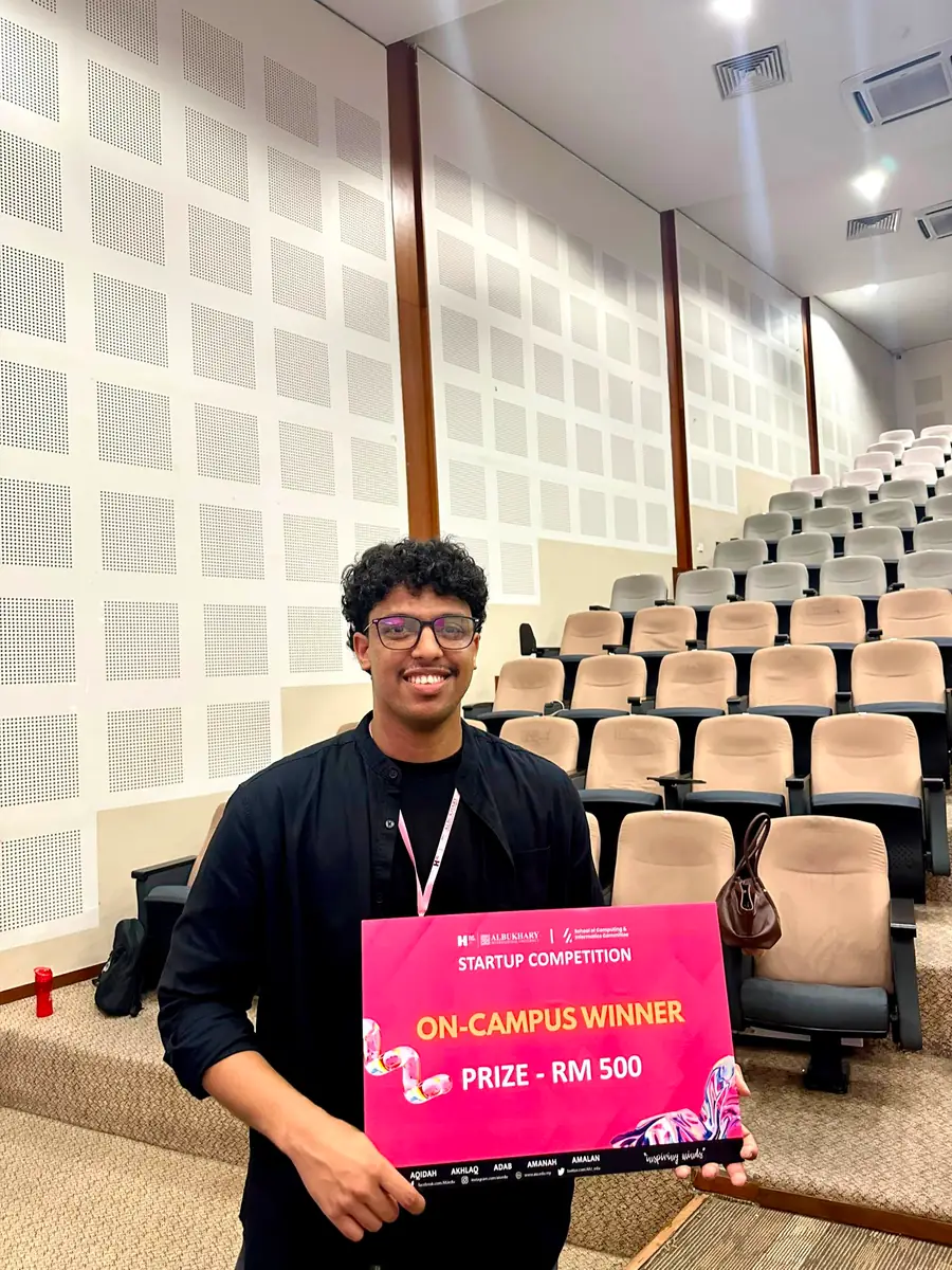 Holding a board reading "Startup Competition — On-Campus Winner".